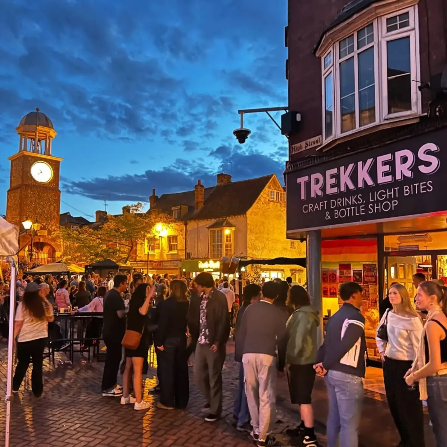 Crowd at dusk in Market Square with the clock tower lit