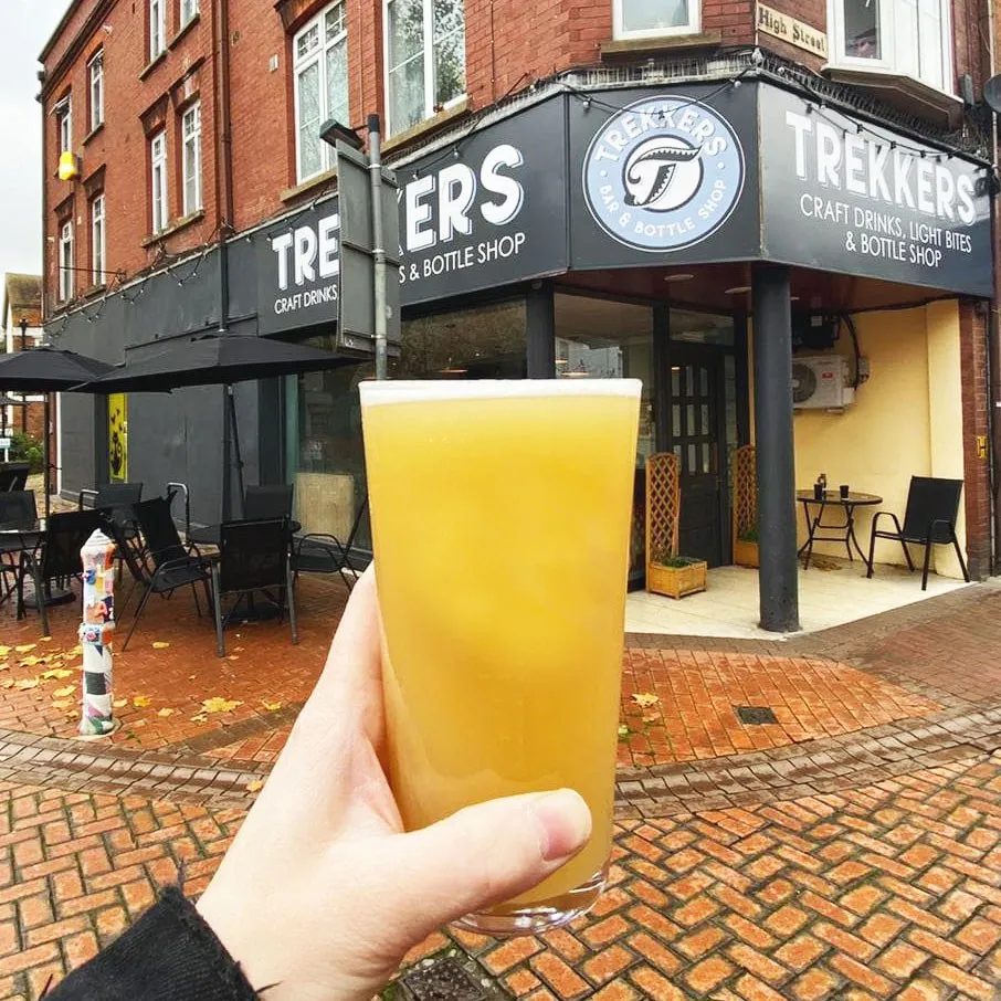 A hazy pint held up outside the shop